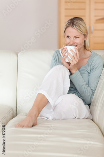 Woman taking a sip of coffee on the sofa