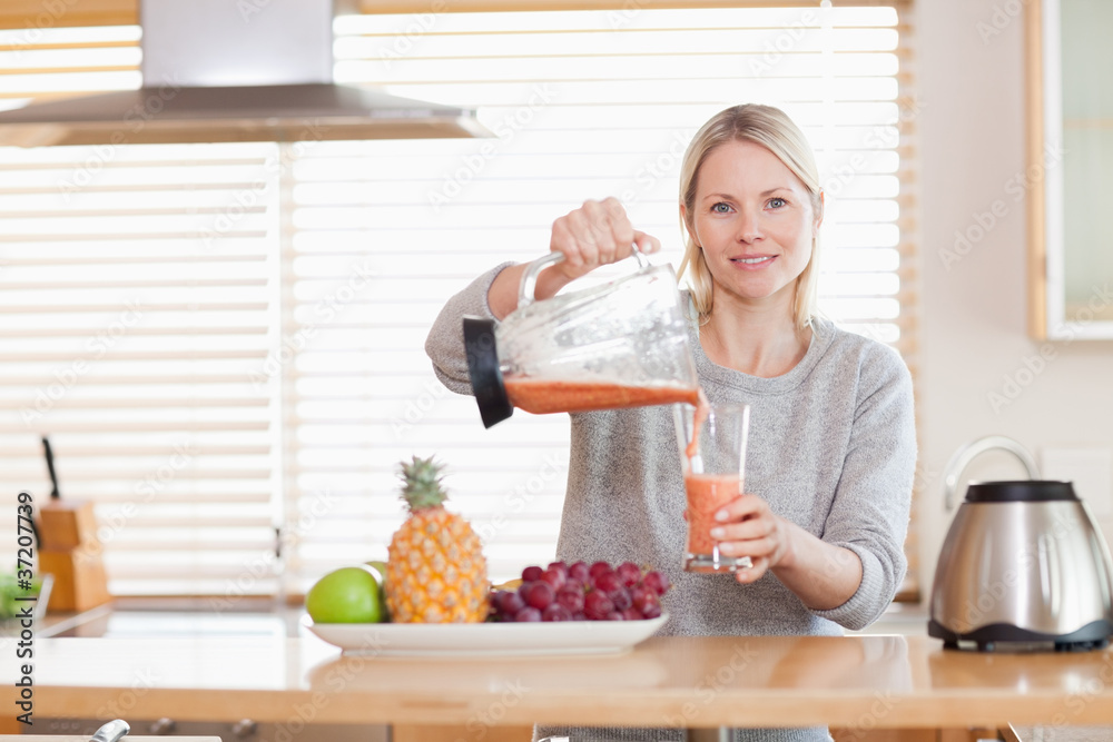 Woman pouring smoothie into a glass