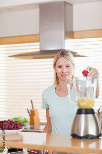 Woman putting strawberry into the blender