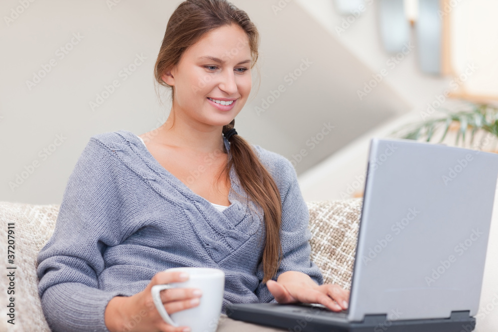 Woman using a laptop while having a tea Woman using a laptop while having a tea