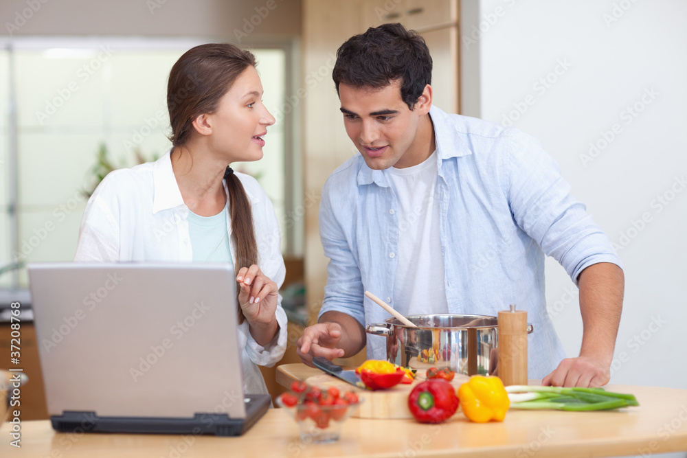 Couple using a notebook to cook