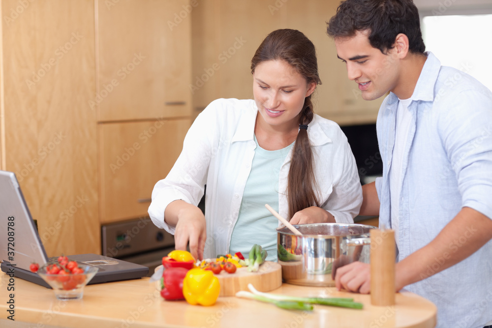 Happy couple using a laptop to cook Happy couple using a laptop to cook