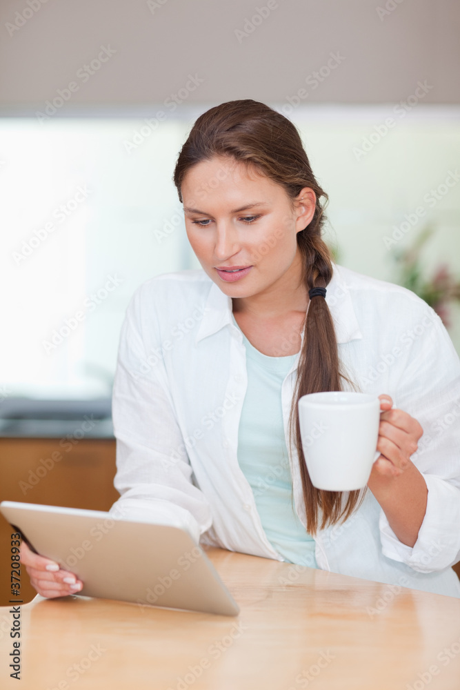 Portrait of a young woman using a tablet computer while drinking Portrait of a young woman using a tablet computer while drinking