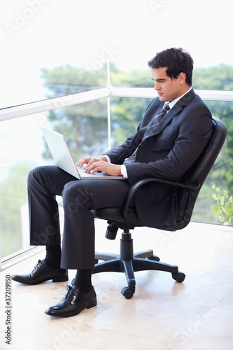Portrait of a businessman sitting on an armchair working with a © WavebreakmediaMicro