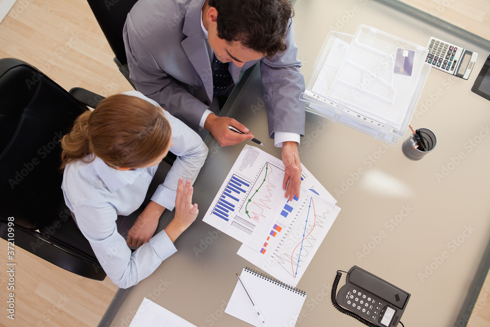 Above view of business people talking about diagram Above view of business people talking about diagram