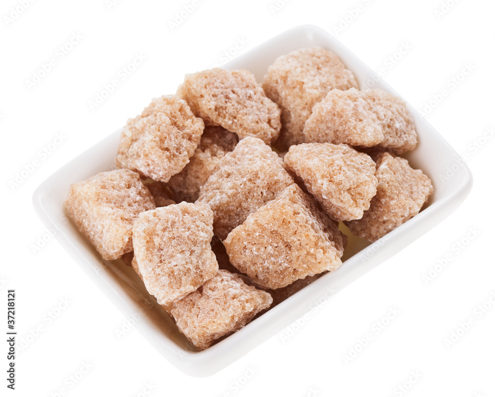 Brown lump cane sugar in a rectangular sugar-basin, isolated on Brown lump cane sugar in a rectangular sugar-basin, isolated on