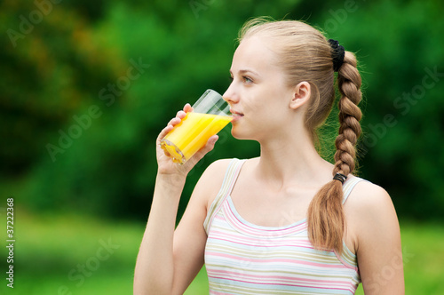 Young woman drinking orange juice. Outdoor