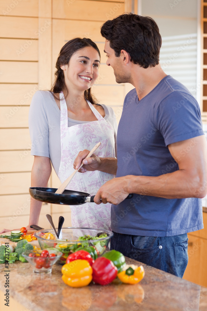 Portrait of a beautiful couple cooking with a pan Portrait of a beautiful couple cooking with a pan