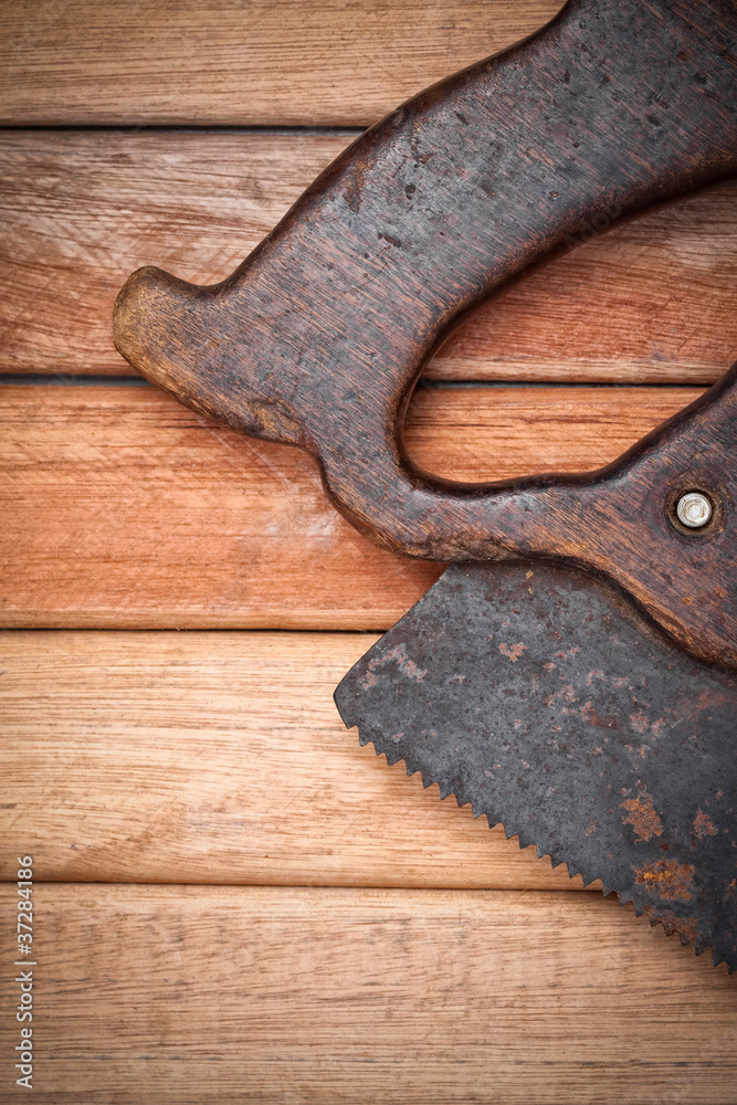 Old handsaw over a wooden boards background with space for text Old handsaw over a wooden boards background with space for text
