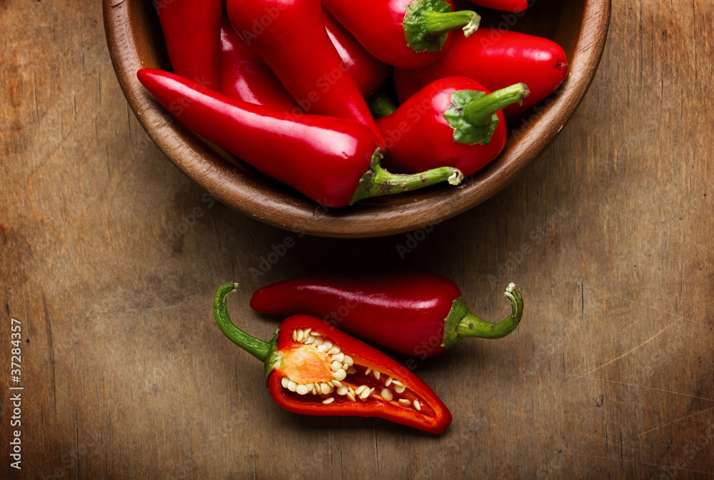 Red Hot Chili Peppers in bowl over wooden background