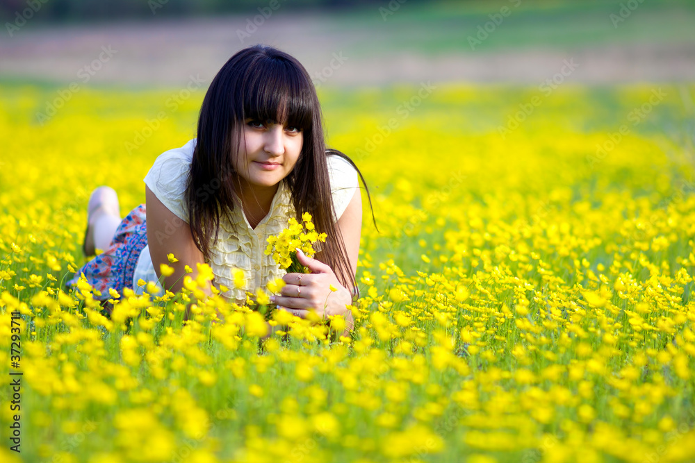 beautiful brunette girl lying in a field of yellow flowers beautiful brunette girl lying in a field of yellow flowers