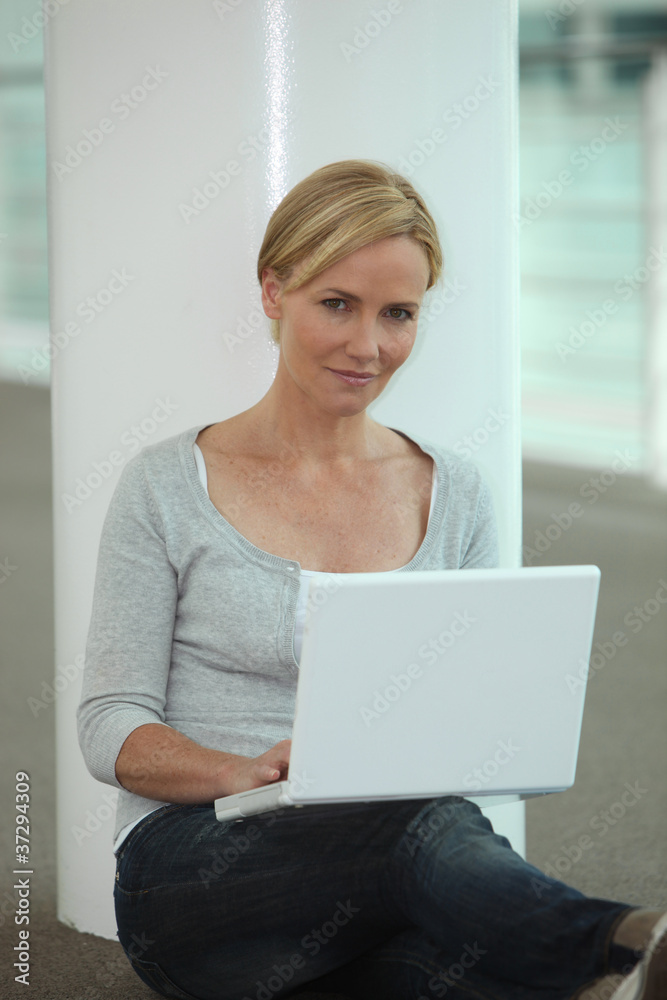 Woman sat next to column using laptop computer Woman sat next to column using laptop computer