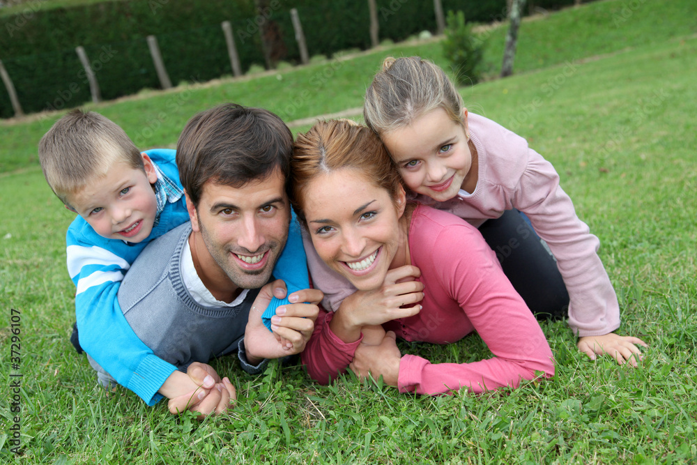 Fototapeta premium Portrait of happy family lying down in grass