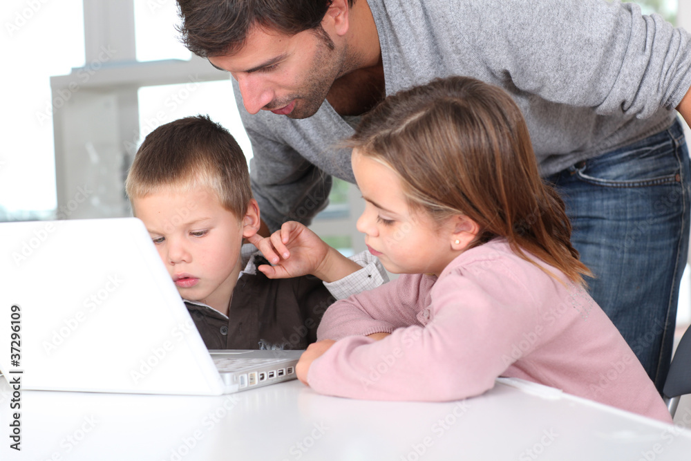Man teaching kids how to use laptop computer Man teaching kids how to use laptop computer