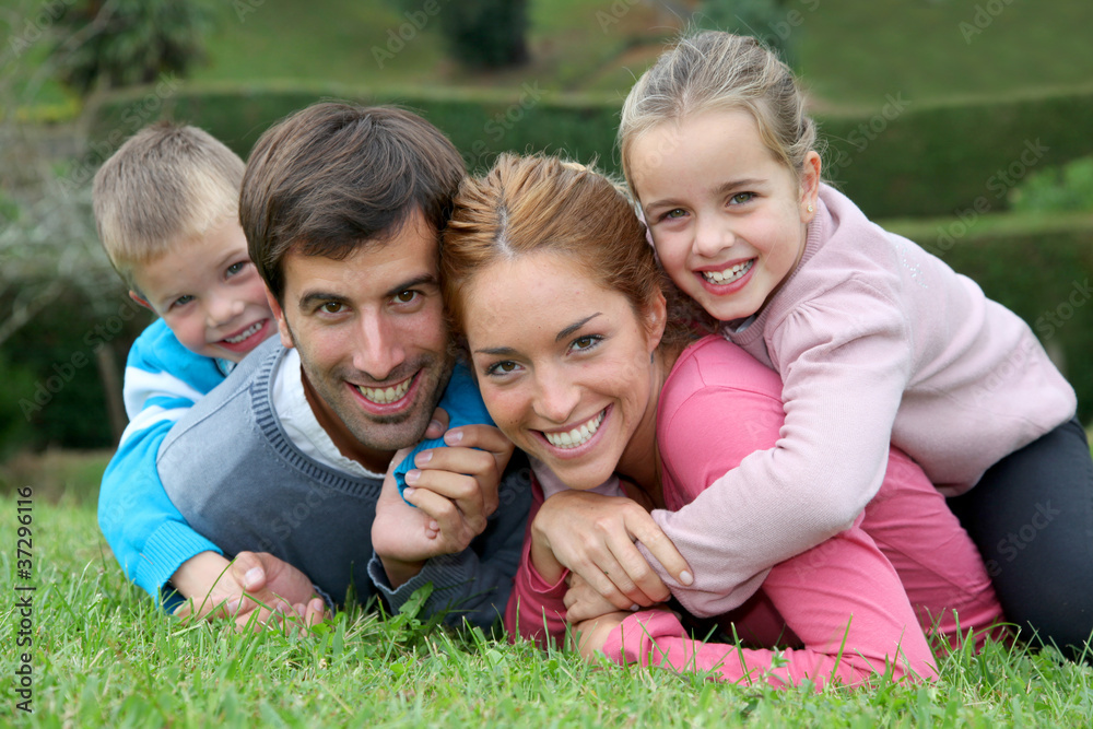 Portrait of happy family lying down in grass Portrait of happy family lying down in grass