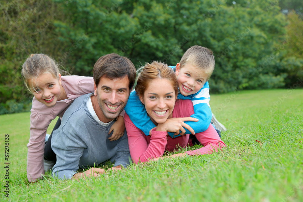 Portrait of happy family lying down in grass Portrait of happy family lying down in grass