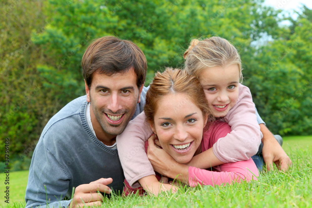 Fototapeta premium Portrait of cheerful family laying on grass