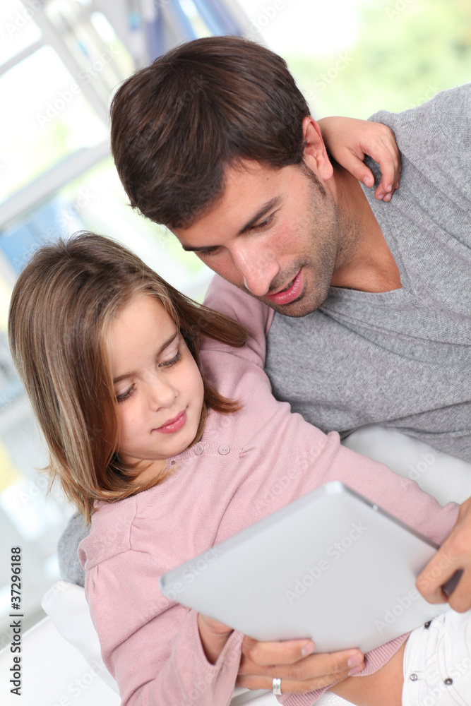 Father and child using electronic tablet at home Father and child using electronic tablet at home