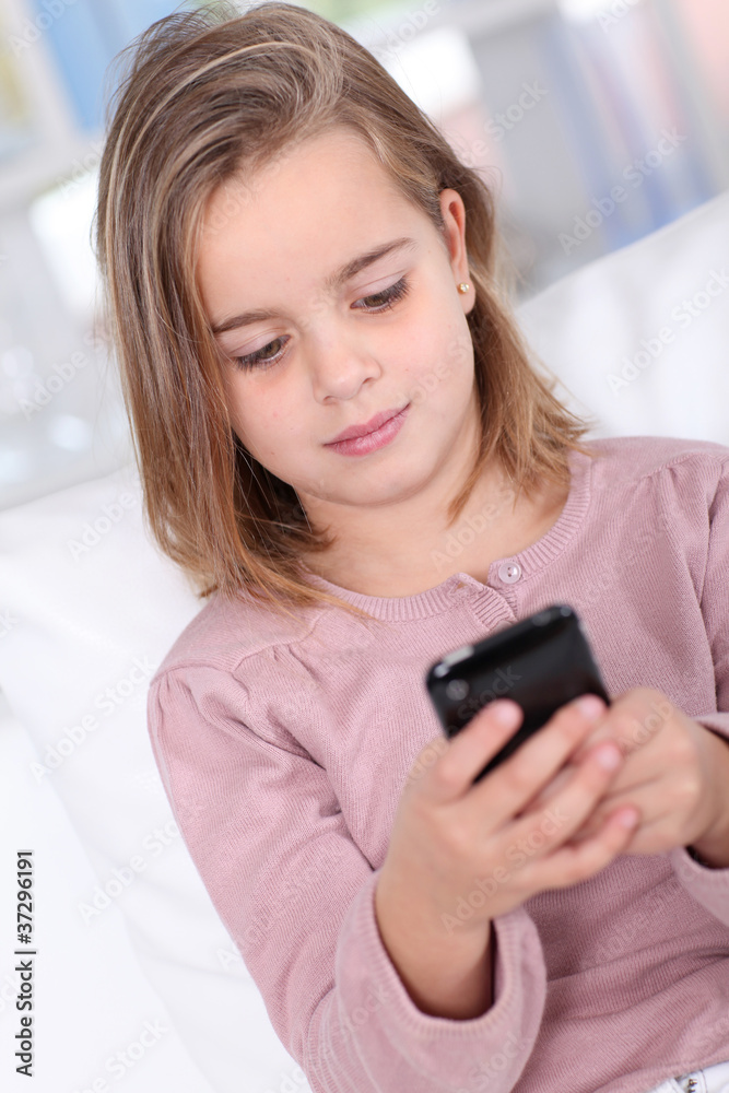 Portrait of little girl writing short message on mobile phone