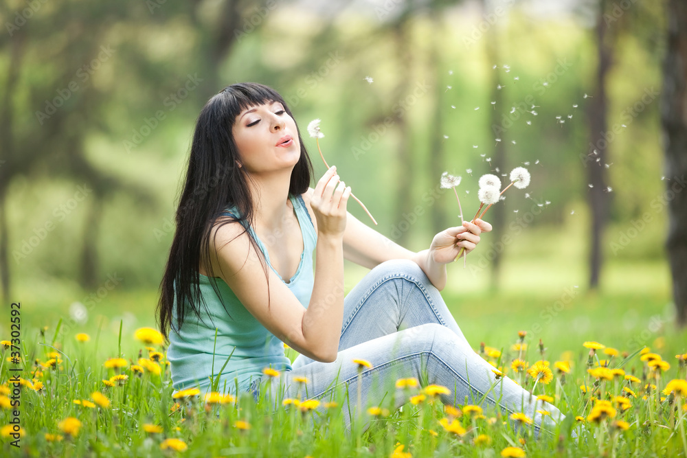 Cute woman in the park with dandelions