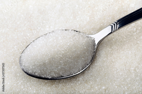 Tea spoon of white granulated sugar photo