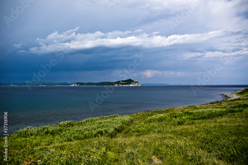 The gras beach on the dramatic sky background. The coast of the Pacific Ocean