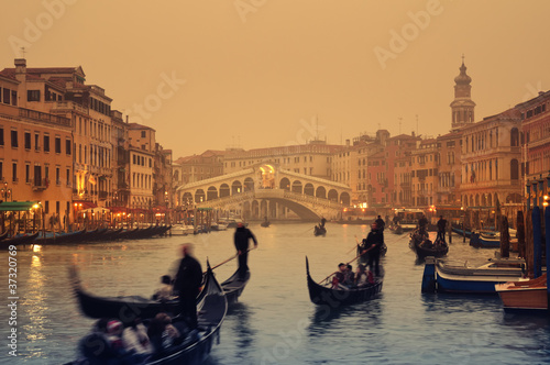 Rialto Bridge and gondolas at a foggy autumn evening in Venice.