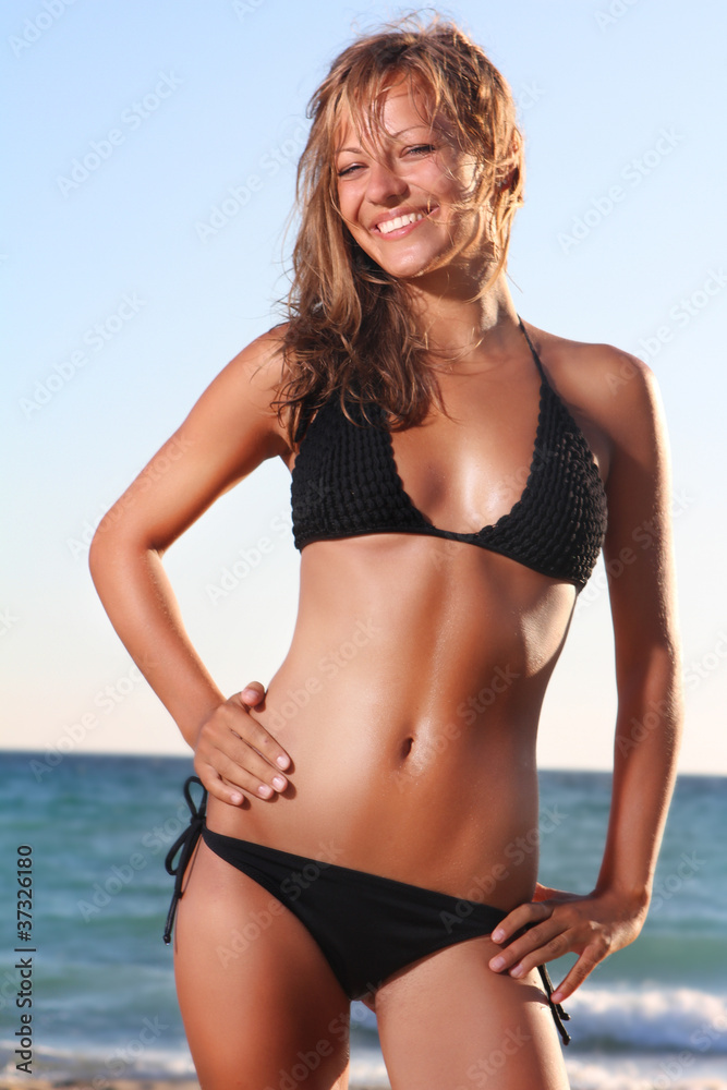 young happy woman in black bikini on sea background