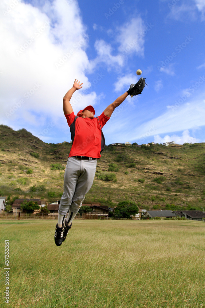 Fototapeta premium Baseball player jumps high to catch a ball