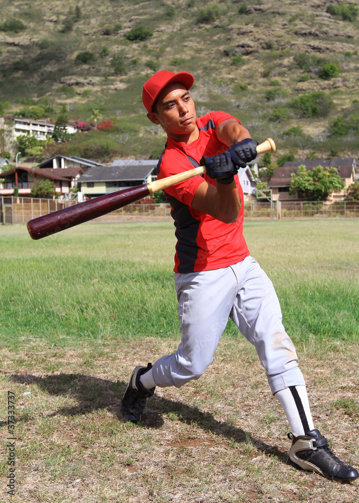 Baseball batter mid-swing in an open grassy field