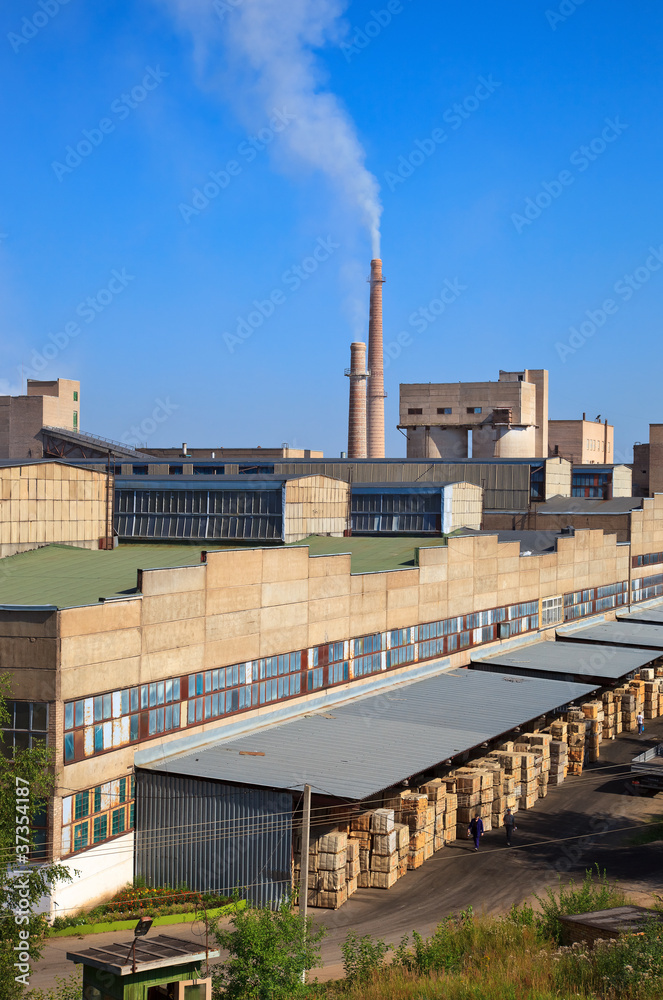 Large factory with smoking chimneys against the blue sky Large factory with smoking chimneys against the blue sky