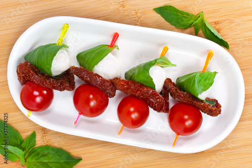 Canapes with cherry tomato, mozzarella, dried tomatoes and basil