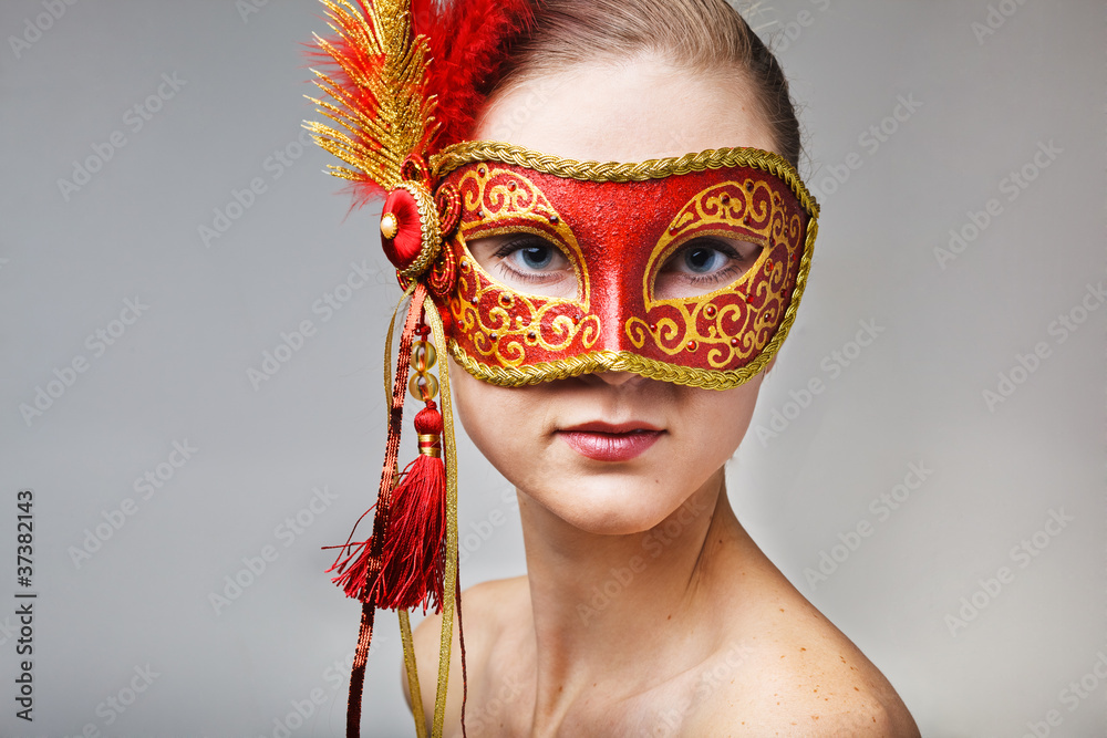 Portrait of beautiful young woman wearing red carnival mask