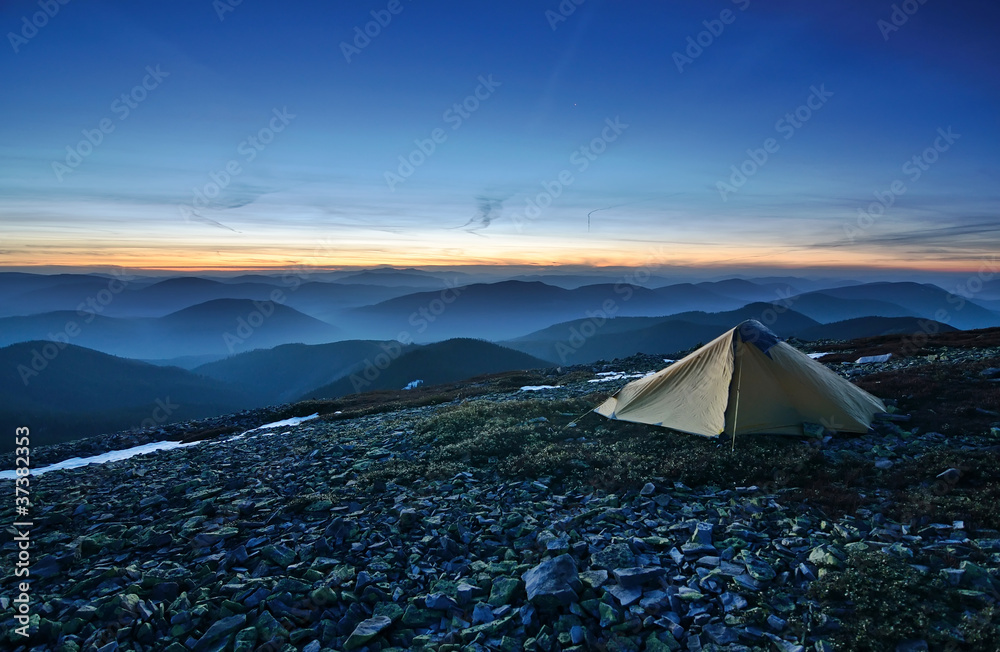 Tourist tent in the rocky mountains and first star