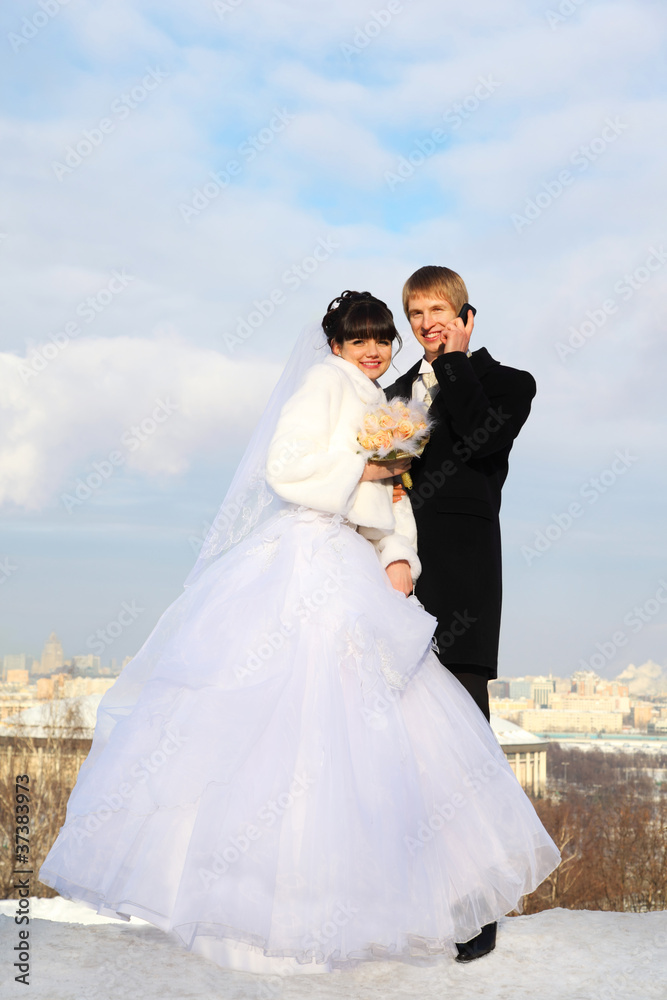 happy groom and bride with bouquet of roses embrace and look