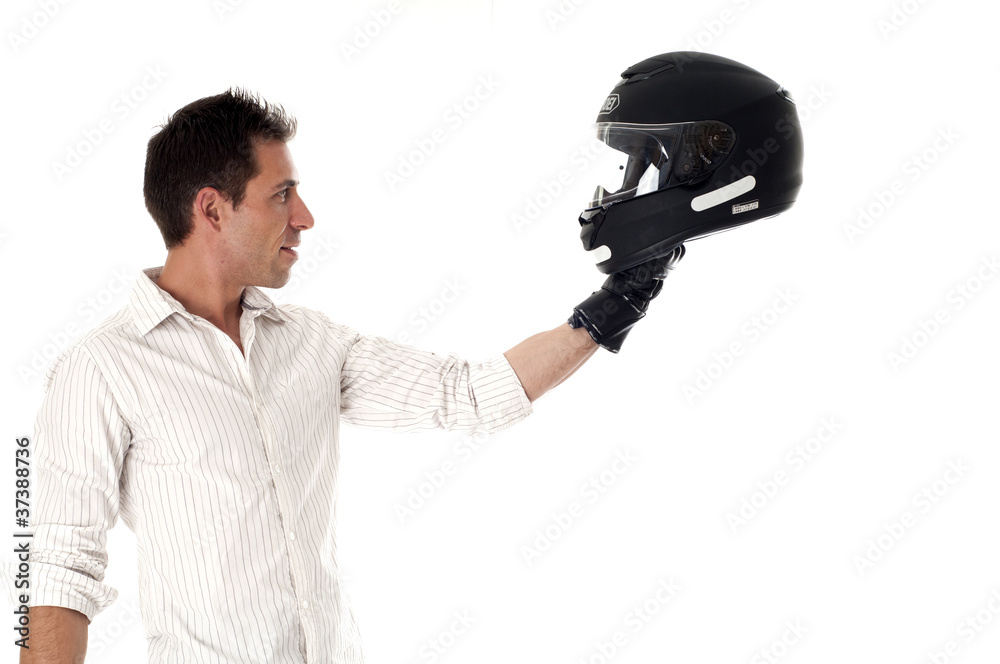 Homme debout de profil tenant son casque de moto