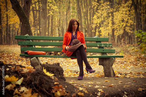 girl sitting on a park bench in late autumn photo