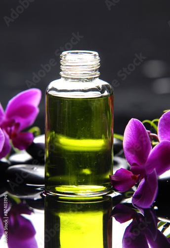 Reflection of bottle of essential oil and pink orchid