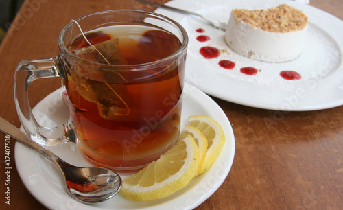 A cup of tea with lemon and a cake