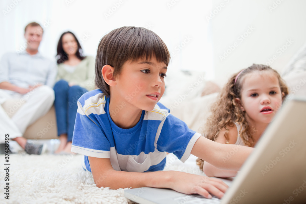 Kids playing computer games on the carpet with parents behind th Kids playing computer games on the carpet with parents behind th
