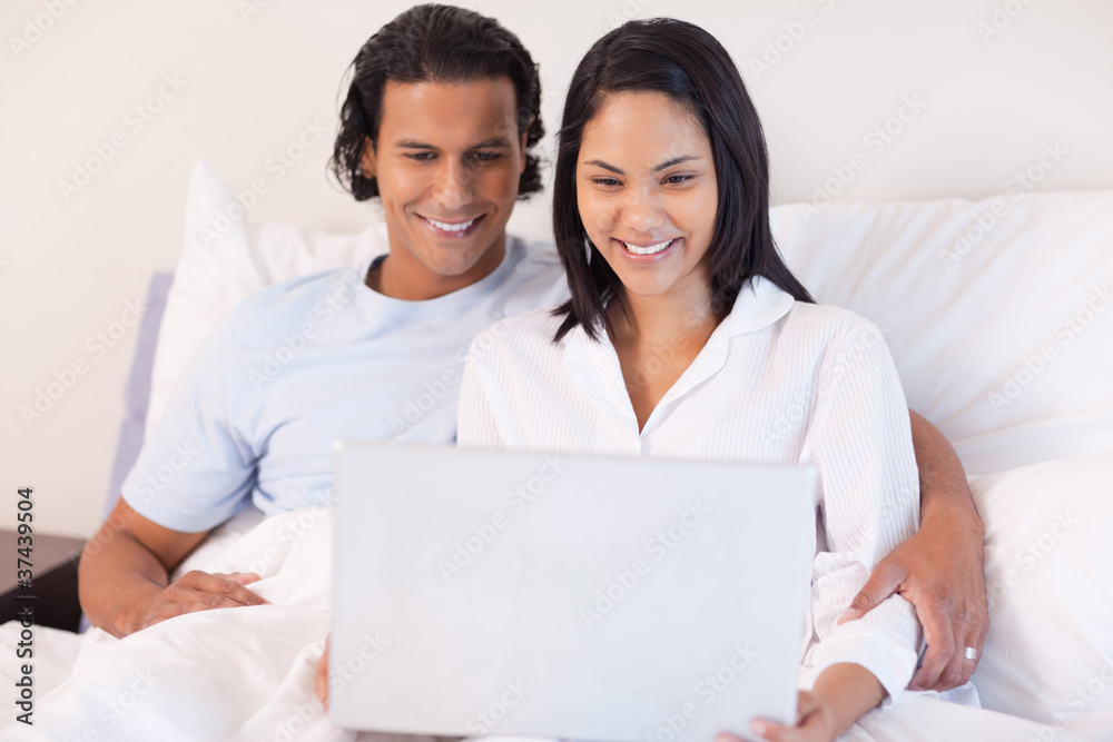 Couple sitting on the bed with their laptop Couple sitting on the bed with their laptop