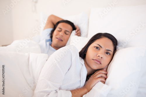 Woman lying awake next to her sleeping boyfriend