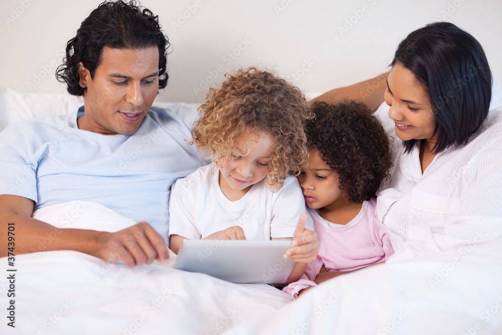 Family sitting on the bed using tablet Family sitting on the bed using tablet