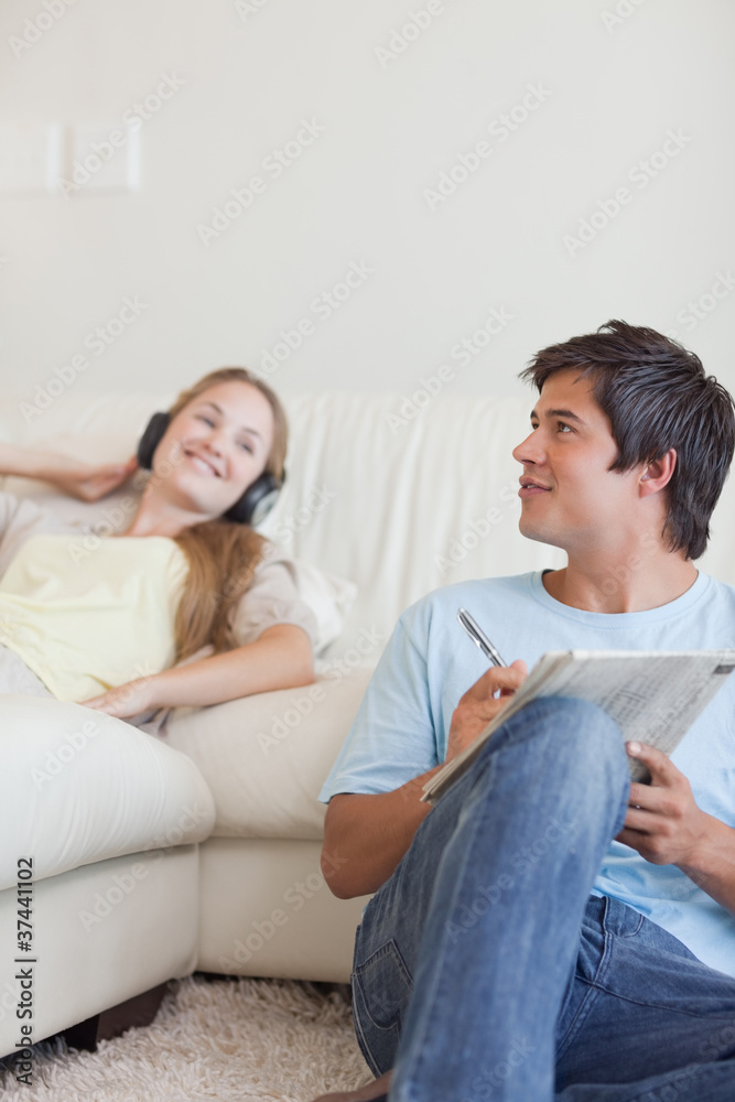 Portrait of a man doing crosswords while his girlfriend is liste Portrait of a man doing crosswords while his girlfriend is liste
