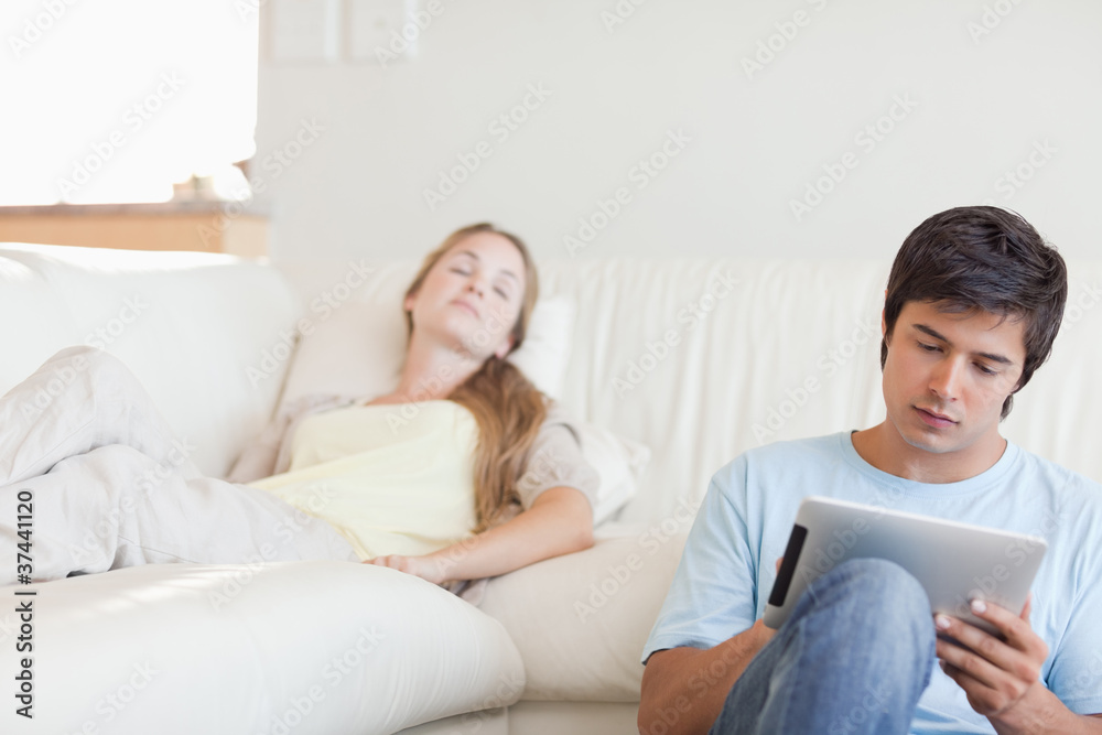 Man using a tablet computer while his girlfriend is sleeping Man using a tablet computer while his girlfriend is sleeping