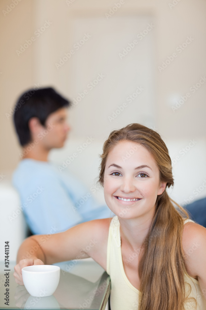 Portrait of a woman having a coffee while her husband is sitting Portrait of a woman having a coffee while her husband is sitting