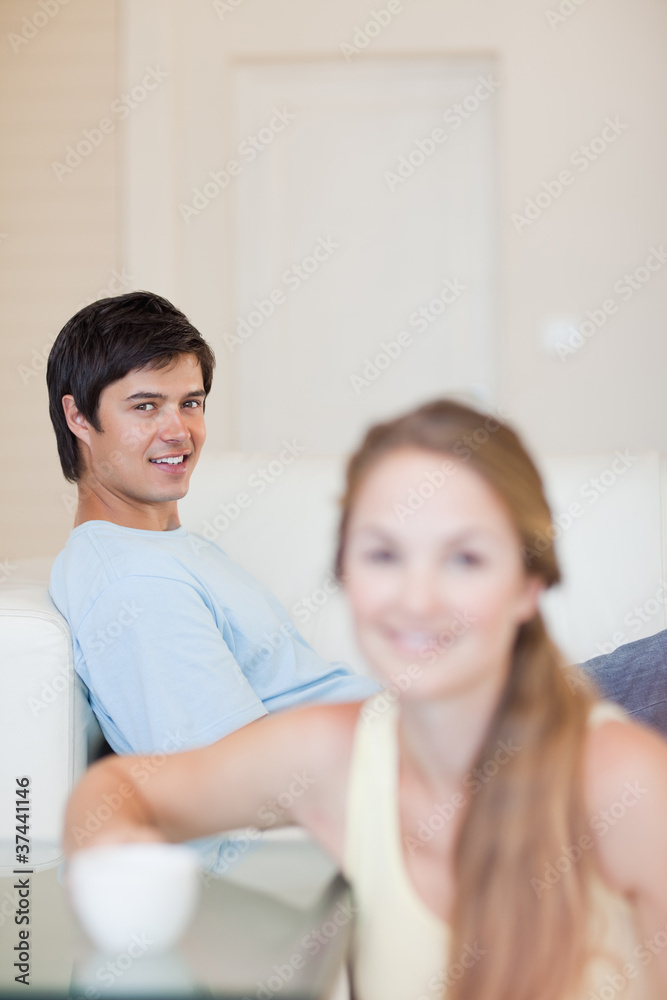 Portrait of a woman having a tea while her fiance is sitting on Portrait of a woman having a tea while her fiance is sitting on
