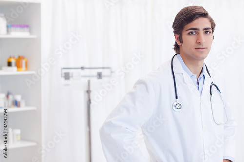 Young doctor standing in his examination room