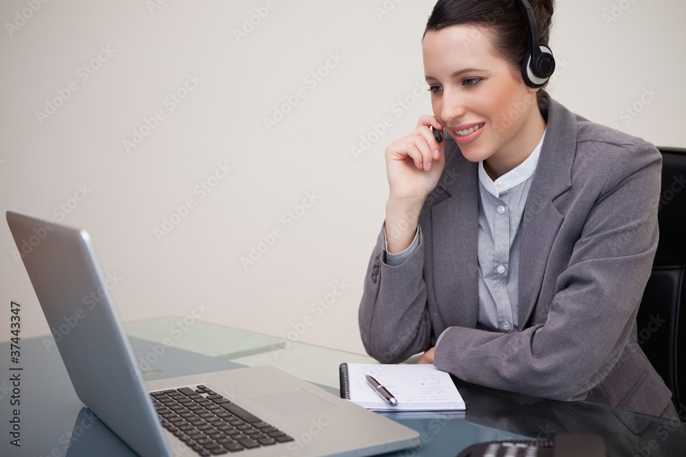 Businesswoman with headset on her laptop Businesswoman with headset on her laptop