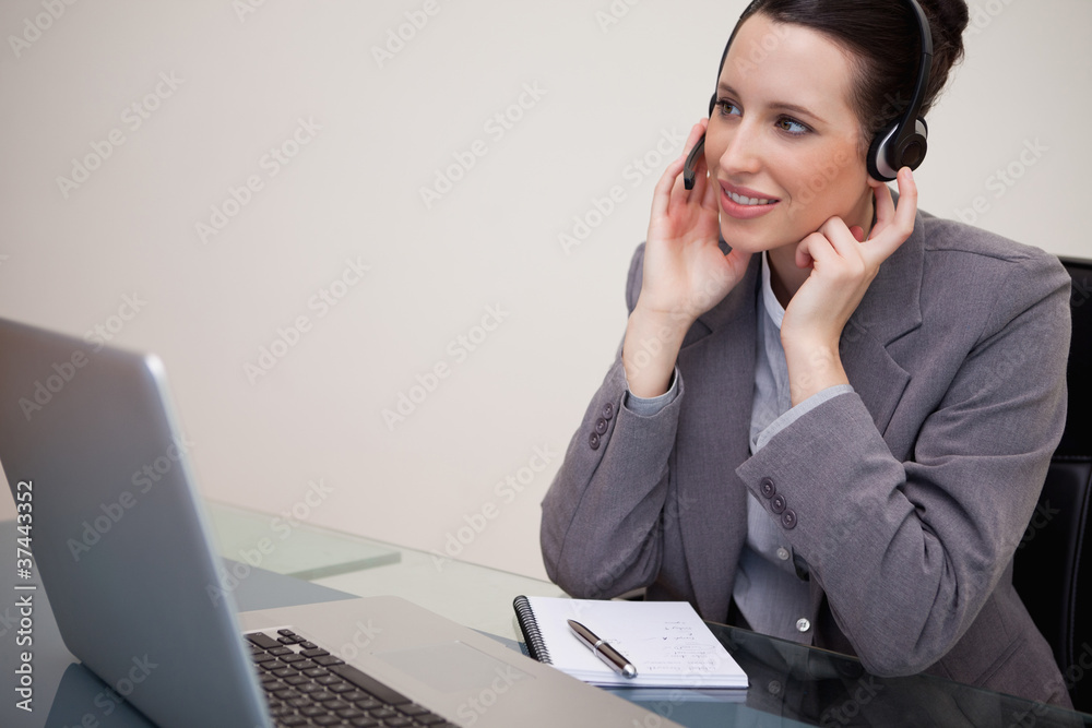 Businesswoman with headset sitting at her desk Businesswoman with headset sitting at her desk